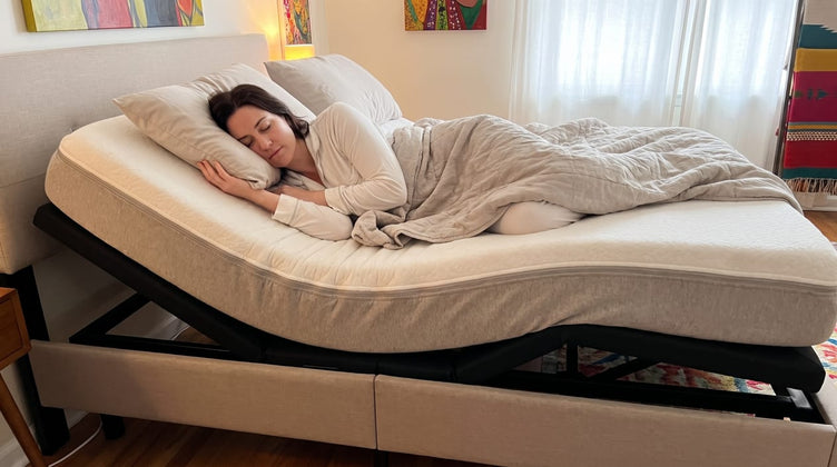 Woman side-sleeping on an adjustable bed with the head raised inside a beige upholstered surround