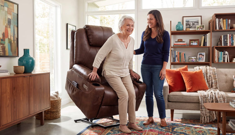 Adult daughter helping her aging mother stand from a brown lift recliner in a living room