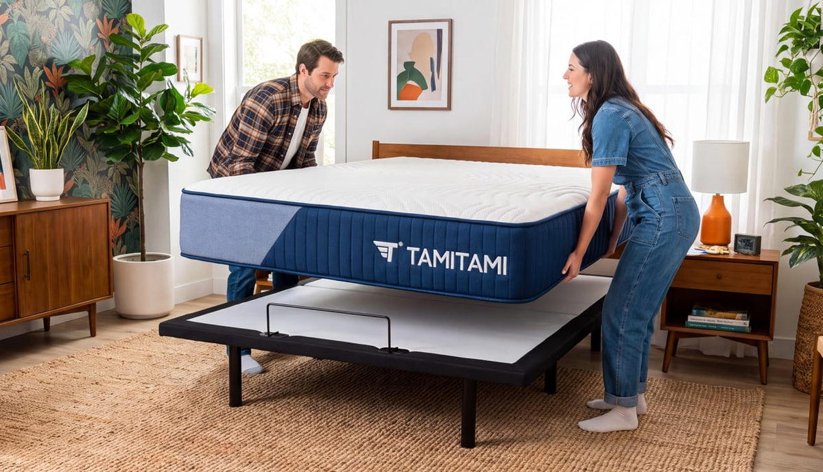 Couple placing a TAMITAMI mattress onto a black adjustable bed base with a retainer bar